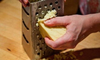 Кусочек сыра натираем на терке с большими отверстиями. По желанию вы можете измельчить сыр на более мелкой терке.