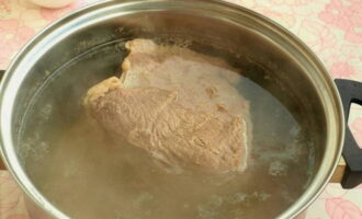 Говядину промываем и удаляем лишний жир. Выкладываем мясо в кастрюлю и заливаем холодной очищенной водой. Когда жидкость закипит, засыпаем к мясу специи, перемешиваем бульон и варим мясо 2 часа. Затем бульон нужно слить в отдельную емкость, а мясо порезать небольшими кусочками.