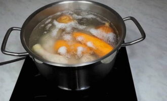 Лук хорошо промываем и отправляем в кастрюлю к курице. Далее кладём туда очищенную морковь, заливаем туда примерно 1.5 литра воды, отправляем на огонь, доводим бульон до кипения и снимаем образовавшуюся пену.