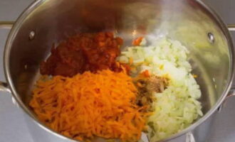 Когда лук станет полупрозрачным – добавляем натертую на терке морковь, томатную пасту и ароматную приправу – перемешиваем и готовим около 5 минут.
