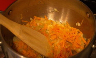 В кастрюлю с толстым дном наливаем растительное масло и обжариваем лук до прозрачности, после засыпаем морковку, перемешиваем и готовим до мягкости.