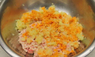 Очищаем луковицу и морковь, промываем корнеплод проточной водой и нарезаем оба продукта крупными кусками. Затем пропускаем их через мясорубку прямо в миску с мясным фаршем.
