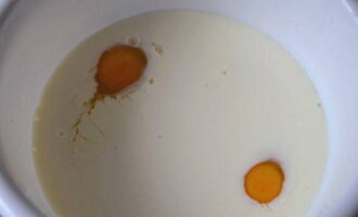 Как испечь пышные блины на дрожжах? В миску влейте теплое молоко и разбейте яйца.