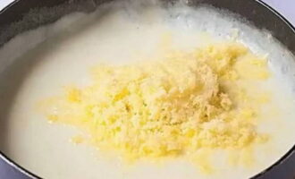 Вливаем в сковороду молоко комнатной температуры и, не переставая мешать, томим около 4-5 минут, солим по вкусу. После, засыпаем сыр и снова перемешиваем.