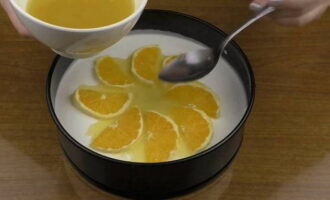 Вымытый апельсин нарезаем кружочками (не слишком тонко). Освобождаем ломтики от кожуры и разрезаем пополам. Нагреваем апельсиновый сок и растворяем в нем остатки желатина. Достаем из холодильника форму с заготовкой и украшаем чизкейк апельсинами. Поливаем их небольшим количеством смеси из сока и желатина.