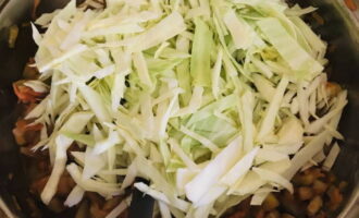 Мелко шинкуем белокочанную капусту. Выкладываем ее к остальным овощам.