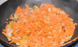 Измельчаем очищенную и вымытую морковь на крупной терке, а затем перекладываем в другую глубокую посуду. Разогреваем остатки растительного масла в сковороде и всыпаем лук. Обжариваем его, постоянно помешивая лопаткой. Добавляем морковь. Обжариваем овощи до золотистого цвета.