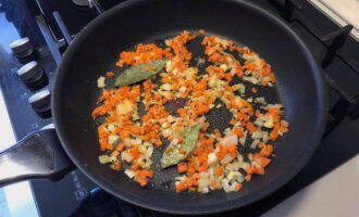 Вторую половину луковицы и зубчик чеснока мелко нарежьте. Морковь нарежьте кубиками.  На растительном масле обжарьте лук, чеснок и морковь до мягкости. Добавьте лавровый лист и жарьте еще 2 минуты.