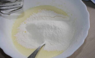 Затем в миску просейте смесь муки и разрыхлителя для теста, всыпьте соль, замесите тесто.