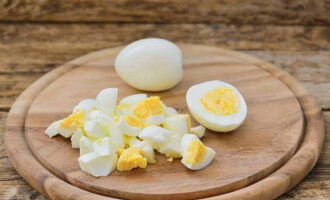 Вареные яйца очистите от скорлупы и нарежьте кубиками.