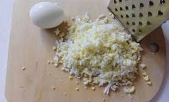 Куриные яйца опустите в кипящую воду и варите 10 минут. Затем остудите, очистите скорлупу и натрите яйца на крупной терке.