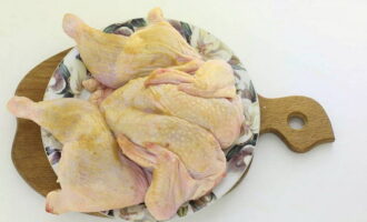 Куриную тушку разрежьте по середине грудки и разверните ее, смажьте со всех сторон подготовленным маринадом. При наличии времени, курицу можно оставить мариноваться в холодильнике на несколько часов.