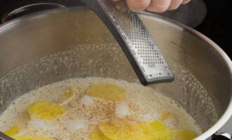 Картофель выложите в кастрюлю, влейте сливки и проварите овощ 10 минут. Затем добавьте измельченный чеснок, соль, мускатный орех и молотый перец.