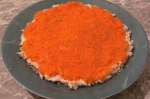 Вареную морковку очистите, натрите на крупной терке и положите ее следующим слоем, нанесите майонезную сетку на него.