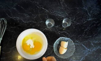 В отдельной пиале перемешайте вилкой два куриных яйца с солью и пищевой содой.