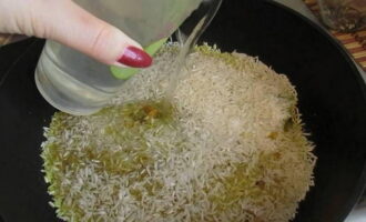 Солим рис по вкусу и перемешиваем. Держим рис со специями пару минут на плите, чтобы крупа впитала все ароматы. Вливаем 200 миллилитров воды.
