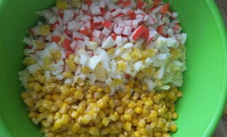 Выложите измельченные ингредиенты в миску, добавьте консервированную кукурузу.