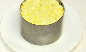 Теперь возьмите кулинарное кольцо и выложите салат слоями в следующем порядке: половина яиц, консервированный ананас, крабовые палочки, сыр, кукуруза и оставшаяся часть яиц.
