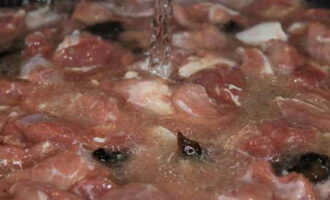 Продолжайте жарить мясо, пока не выпарится жидкость. Затем влейте столько холодной воды, чтобы она превышала мясо на 1 сантиметр.