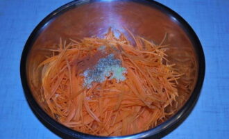 К моркови добавьте измельченный чеснок, кориандр, молотый красный перец и растительное масло, перемешайте.