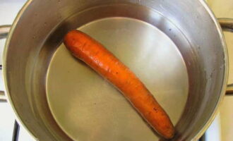 Промываем морковь проточной водой. Выбираем емкость, в которой будем ее варить. Если корнеплод не будет вмещаться в посуду для варки, его нужно будет разрезать пополам. Варим морковь до мягкости (предварительно не очищаем ее), проверяем готовность ингредиента ножом. 