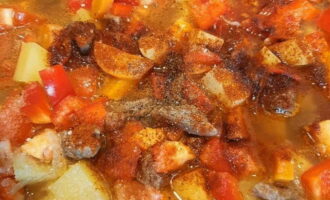 Промытые сладкий перец и помидор нашинкуйте небольшими кубиками и переложите в казан. Затем блюдо посыпьте по своему вкусу солью с черным перцем, добавьте молотую паприку и измельченные на чесночнице зубки чеснока. После закипания, потушите мясо с овощами на небольшом огне и под прикрытой крышкой минут 40, до готовности говядины.