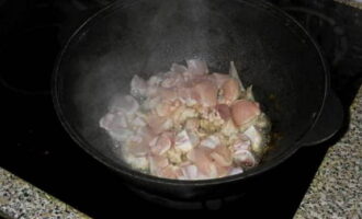 Казан поставьте на плиту, прогрейте его, влейте подсолнечное масло. Далее выложите курицу и обжарьте ее до румяной корочки.