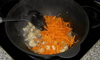 Когда лук подрумянится, добавьте морковь, всыпьте зиру и молотый перец, перемешайте и продолжайте готовить.