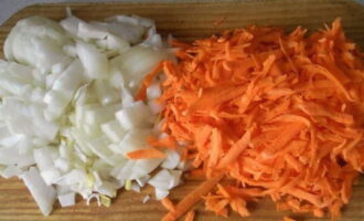 Тем временем очищенную морковку натираем на терке, а оставшийся репчатый лук нарезаем кубиками.