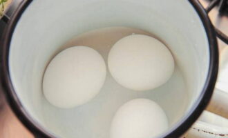 До полной готовности отвариваем три куриных яйца, охлаждаем в ледяной воде и очищаем от скорлупы.