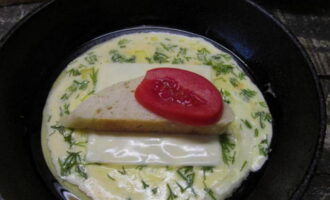 На сыр укладываем кусочек хлеба и пару долек томата. Как только основа схватится, аккуратно заворачиваем края к центру.