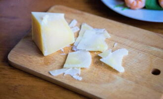 Твердый сыр нарезать острым ножом тонкими слайсами.