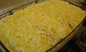 Через 30 минут форму извлеките из духовки и посыпьте блюдо измельченным на крупной терке твердым сыром. Продолжите запекание еще 15 минут.