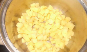Для начала очищаем и хорошо промываем под проточной водой картофель. Далее нарезаем его небольшими кусочками и отправляем в кастрюлю.