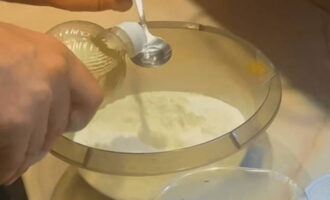 Через густое сито просеивается мука и пересыпается в посуду для замеса теста. Ложкой в горке муки делается небольшое углубление и в него наливается растительное масло.