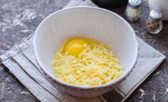 В глубокую пиалу разбиваем яйцо и добавляем твердый сыр, измельченный при помощи терки.