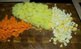 Очищаются отваренные картофель и морковка и нарезаются такими же маленькими кубиками, как и яйца.