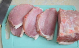 Мясо нарезаем порционными кусочками, толщиной около одного сантиметра. Раскладываем заготовки на разделочную доску, прикрываем пищевой пленкой (чтобы не летели брызги) и отбиваем с двух сторон, предварительно присыпав солью и вашими любимыми специями, которые сочетаются со свининой.