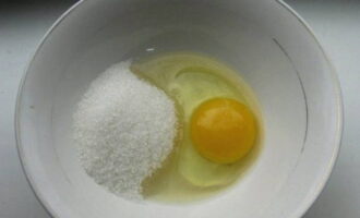 В пиалу разбивается одно куриное яйцо и к нему насыпается сахар обычный и ванильный, соль.