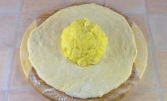 Подготовленный продукт раскатываем в лепешку и в центр кладем шарик из картошки и сыра.