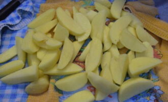 Картофель очистить от кожуры, промыть под проточной водой и нарезать продольными дольками. Затем картофель насухо вытереть салфеткой.