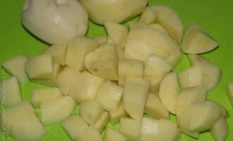Очищенные клубни картошки режем кубиком и пересыпаем в бульон.