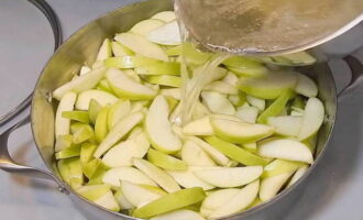 С яблочной нарезки слить подкисленную воду и залить яблоки кипящим сиропом.