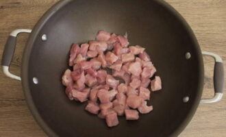 500 граммов свинины сполосните и промокните салфетками. Нарежьте мясо средними по размеру кусочками. Глубокую сковородку раскалите. Налейте растительное масло. Отправьте нарезанную свинину, обжарьте до румяности.