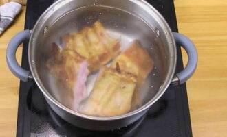 Копченые свиные ребрышки разрежьте по межреберным промежуткам, положите их в кастрюлю для варки супа и залейте холодной водой в расчете на 6 порций супа. Поварите ребрышки течение 30 минут от начала кипения на небольшом огне и под прикрытой крышкой.