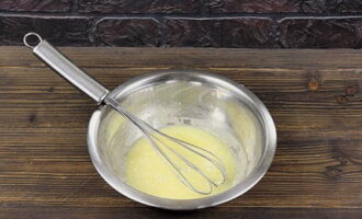 Займитесь приготовлением крема. Молоко нагрейте до появления пузырей. Куриное яйцо предварительно вымойте и обсушите. Разбейте его в глубокую миску. Хорошенько размешайте венчиком со столовой ложкой картофельного крахмала, сахарным песком и ванильным сахаром.