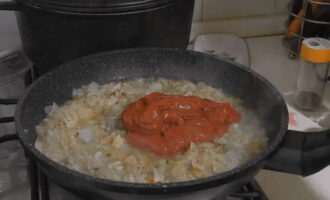К обжаренному с чесноком луку добавить 2 ложки томатной пасты, перемешать и потушить 5 минут.