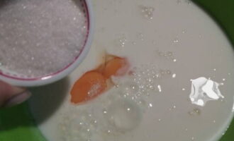 В посуду для замеса теста налейте простоквашу обычной комнатной температуры. В нее разбейте куриные яйца и насыпьте сахар с солью.