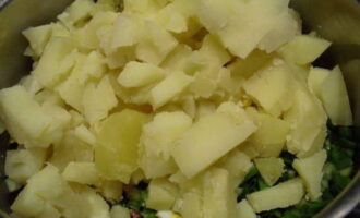 Картофель нарежьте такими же кубиками, как яйцо и огурец. Нарезку лука, яиц и картофеля переложите в салатницу.