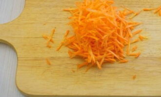 Две морковки сполосните от загрязнений, поскрябайте ножом или очистите с помощью овощечистки. Настругайте соломкой или превратите в стружку с помощью терки.